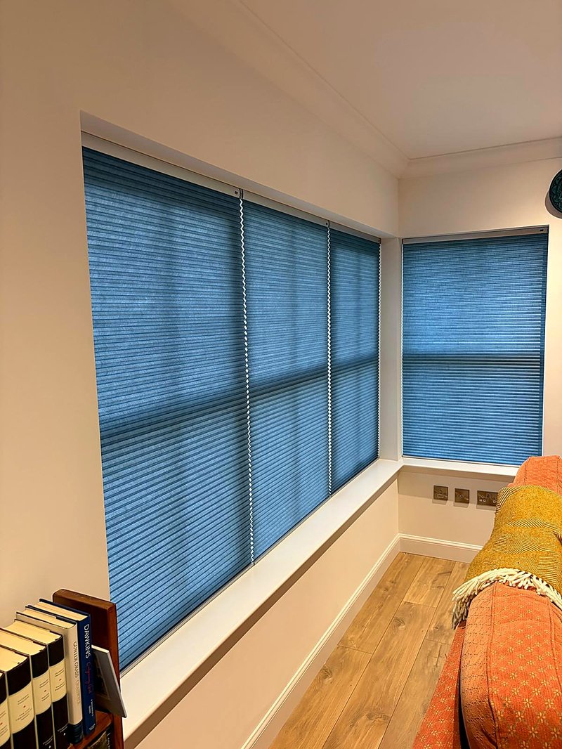 Blue Duette honeycomb blinds fitted to corner windows in a bright living room