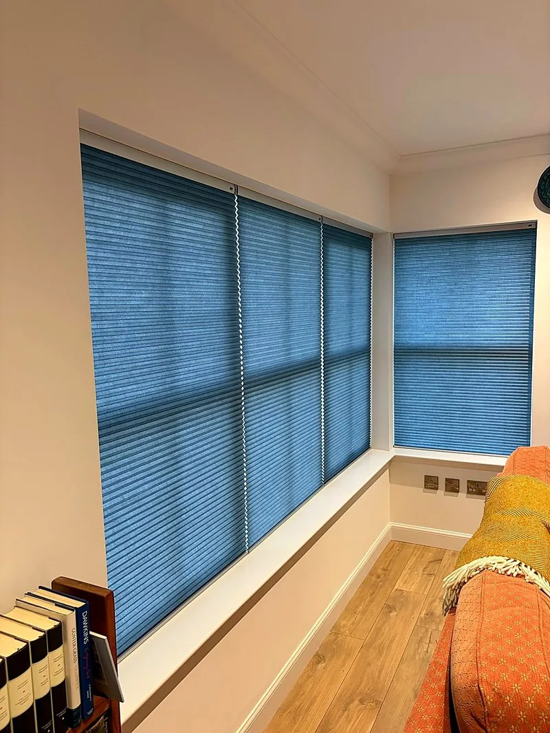Blue Duette honeycomb blinds fitted to corner windows in a bright living room