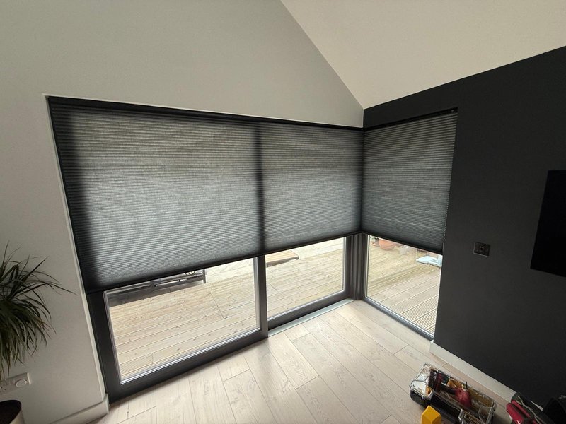 Dark grey Duette blinds on large corner windows with decking view