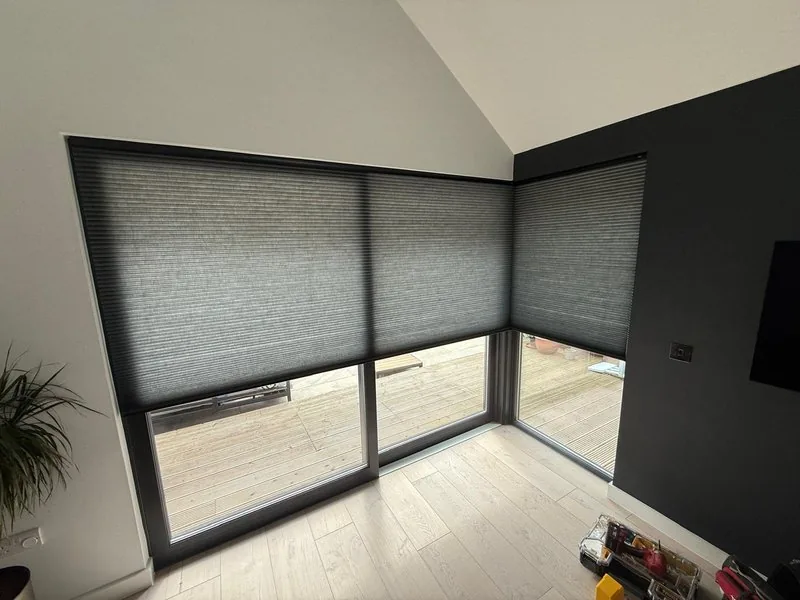 Dark grey Duette blinds on large corner windows with decking view