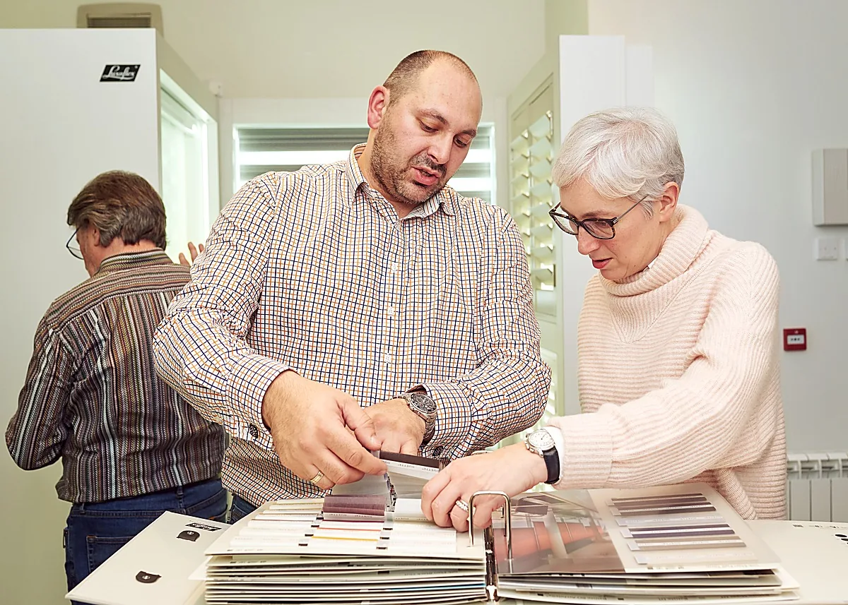 A specialist showing shutter and blind samples to a visitor at the Edinburgh Design Studio