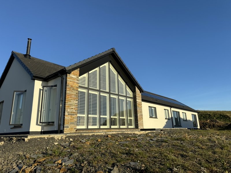 Gable window shutters on a new build home in Orkney with stone walls and blue sky
